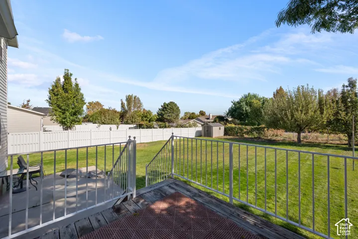 Expansive backyard featuring a manicured lawn, established trees, and a white privacy fence