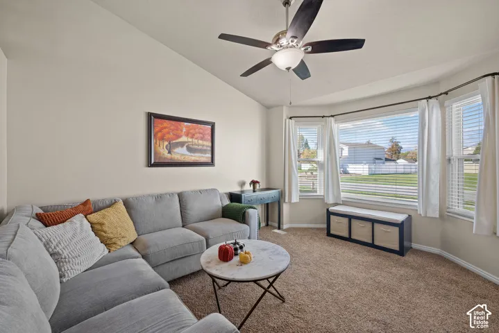 Vaulted ceiling with a ceiling fan, bay window with blinds, and neutral-toned carpet