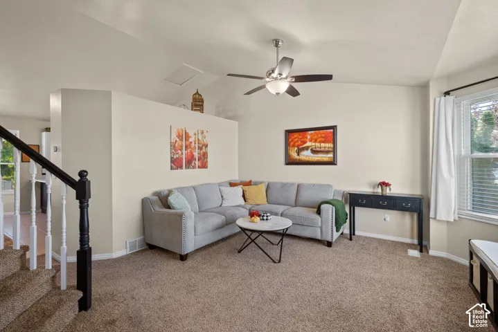 Vaulted ceiling with a ceiling fan, carpeted flooring, and a multi-pane window with blinds