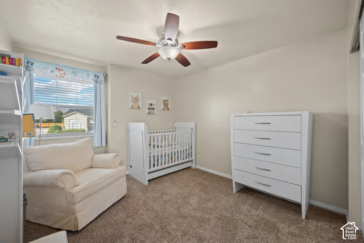 Recessed window with blinds, ceiling fan with light fixture, neutral wall paint, and textured carpeting