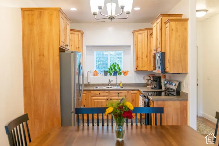 Kitchen with wood cabinetry, light-colored countertops, stainless steel appliances, and a window above the sink