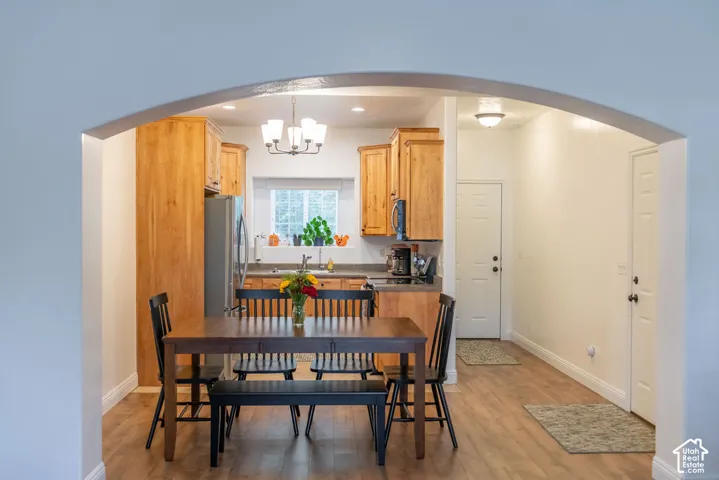 Arched entryway opening to a dining area with wood-finish flooring