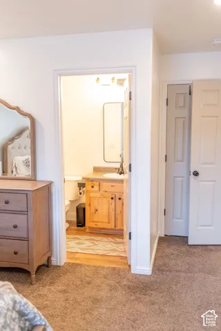 Wood-finish flooring in bathroom with a wood vanity and a built-in sink