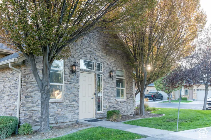 Stone veneer exterior with multiple windows, a paneled entry door, and decorative outdoor lighting