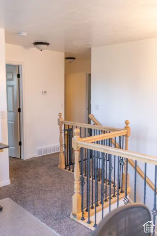 Carpeted hallway with a wood and wrought iron staircase