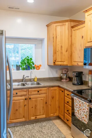 Wood-finish cabinetry and countertops, with a stainless steel double basin sink and a stainless steel electric range