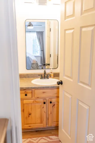 Wood-finish vanity with a drop-in sink, dark bronze faucet, and black hardware