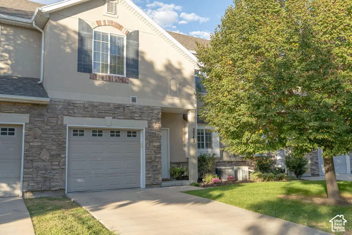 Stone facade with stucco siding, arched window with shutters, and an attached garage