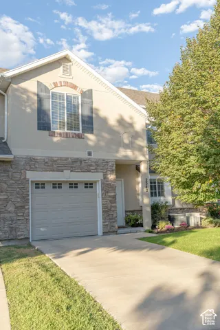 Stucco exterior with stone veneer accents, an arched window with brick detailing, and a multi-panel garage door