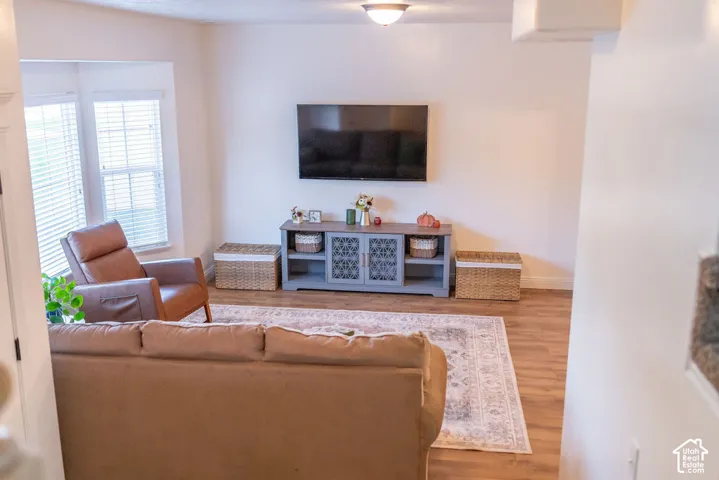 Bay window with horizontal blinds, wood-finish flooring, and recessed ceiling lighting