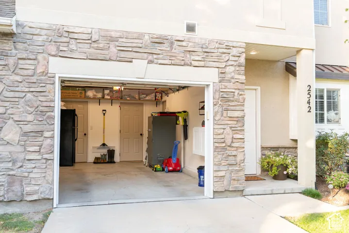 Attached garage with a concrete floor, stone veneer exterior, and adjacent covered entryway
