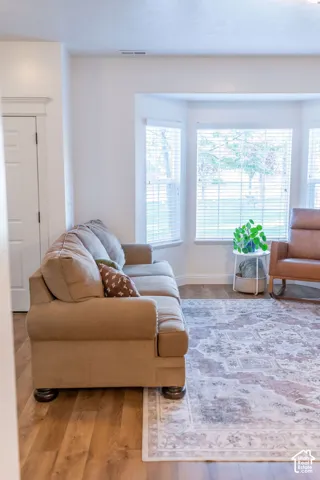 Bay window with multiple panes, crown molding, and wood-finish flooring