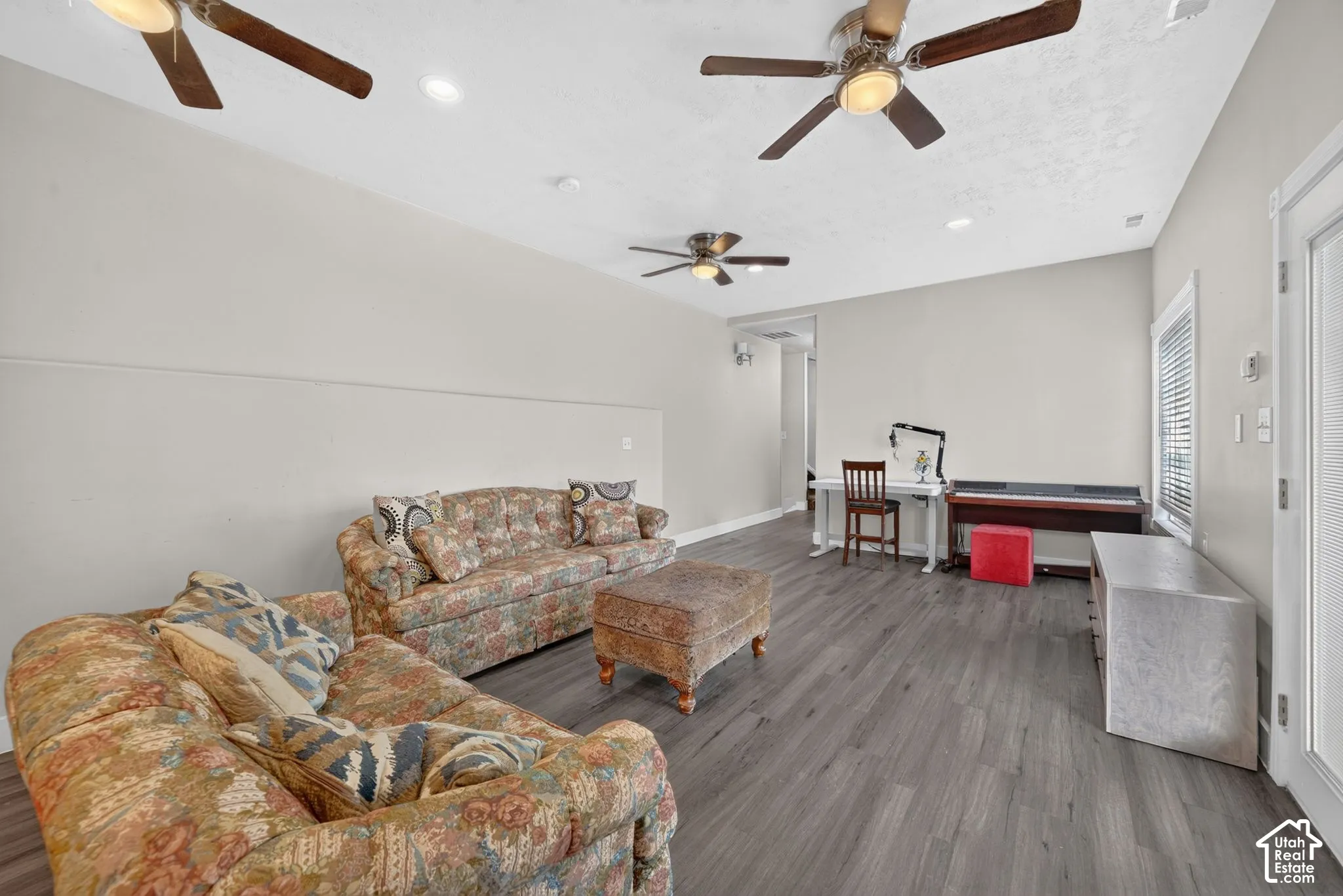 Sloped ceiling with recessed lighting and three ceiling fans, wood-finish flooring, and white painted walls