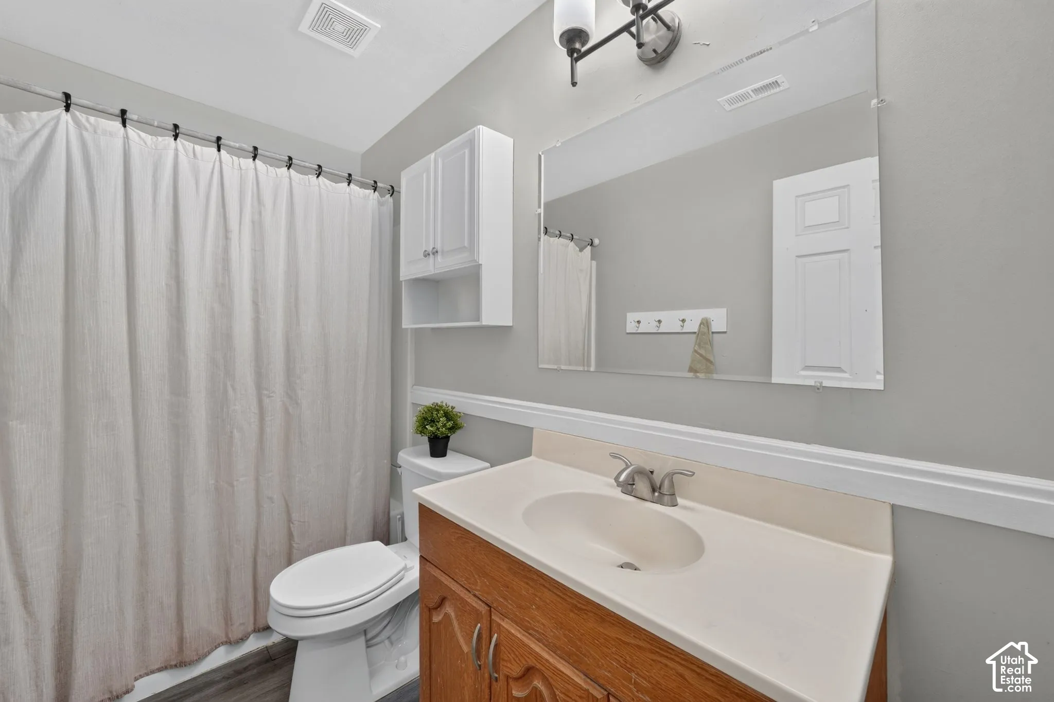 Bathroom featuring wood-finish vanity, integrated sink, and wall-mounted mirror