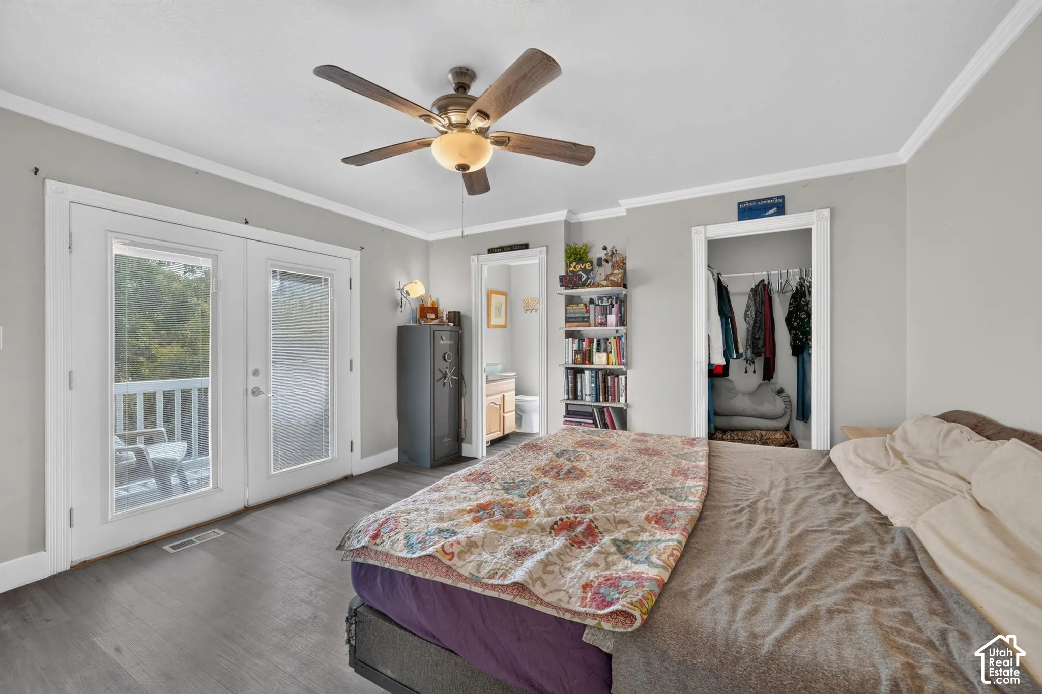 Wood-finish flooring, ceiling fan with integrated lighting, double French doors, white crown molding, and recessed closet
