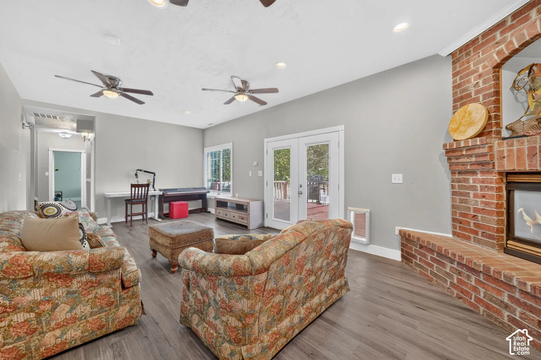 Expansive living space featuring wood-finish flooring, a brick fireplace with hearth, recessed lighting, and double-paned glass doors
