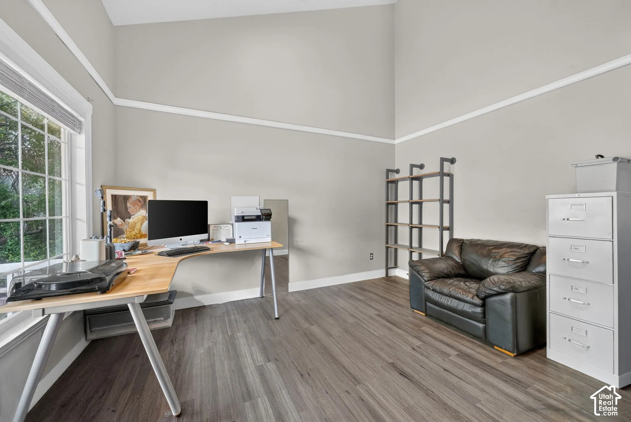 Vaulted ceiling, wood-finish flooring, white crown molding, large window, and light gray wall paint