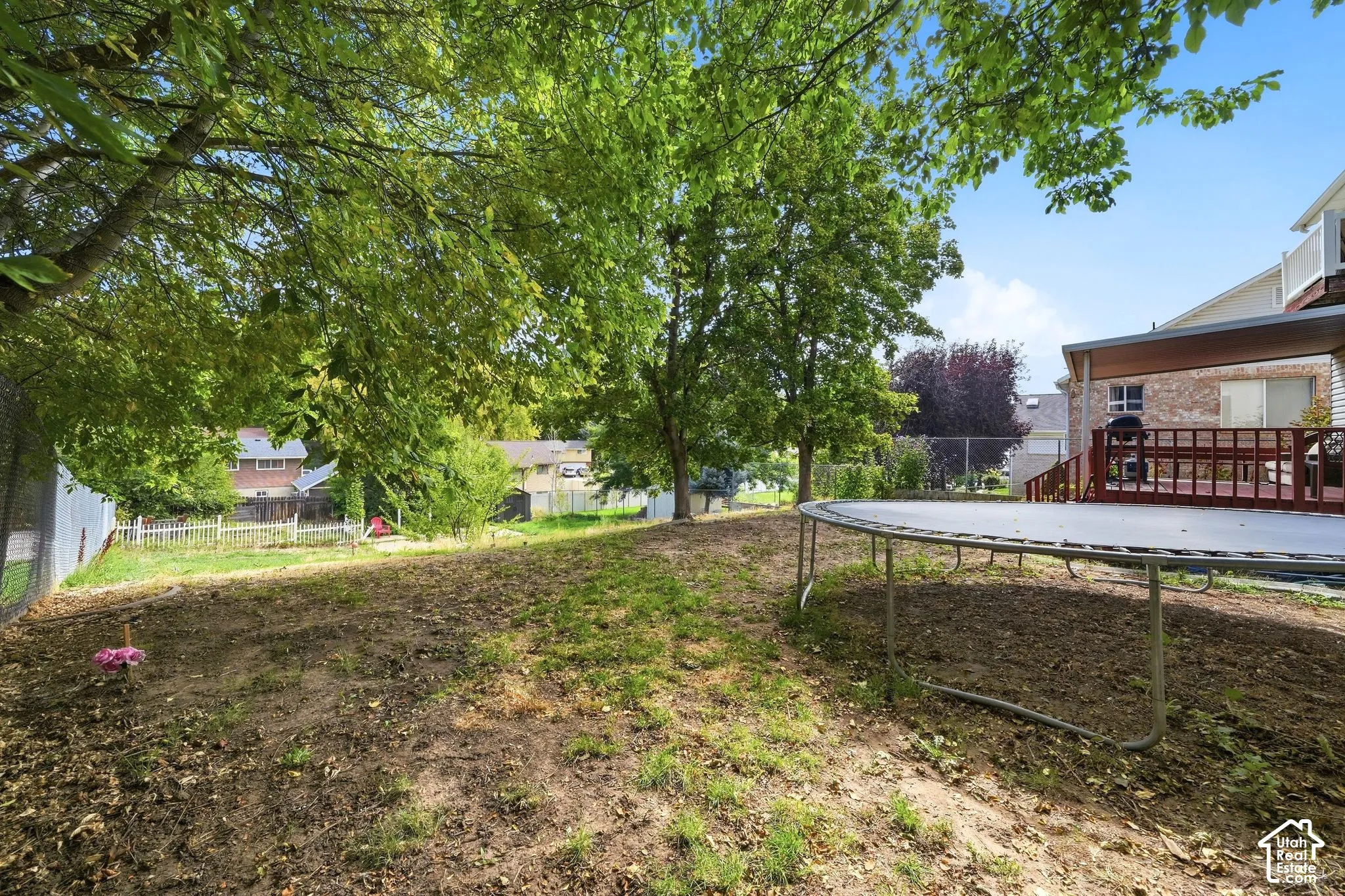 Expansive backyard featuring mature trees, a multi-level deck, and a covered patio area