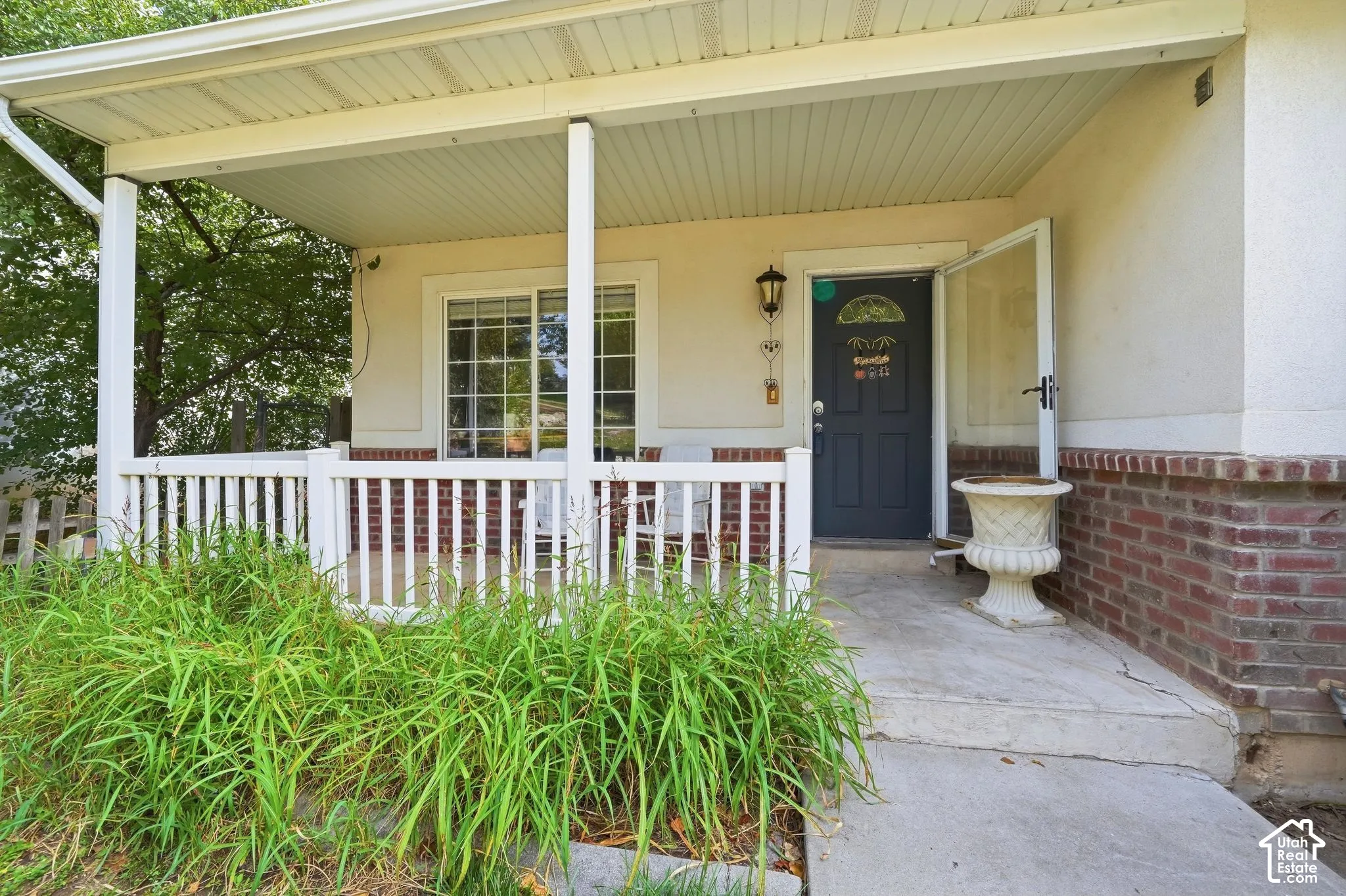 Covered front porch with white railings, brick facade accents, and a dark entry door