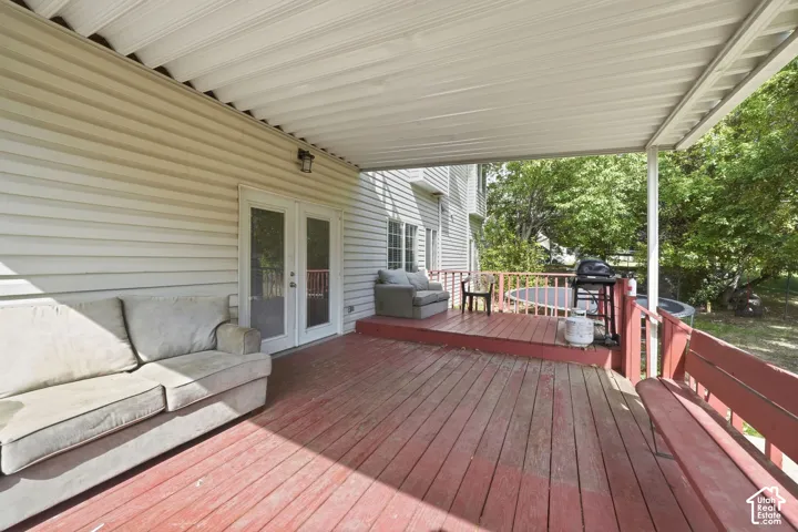 Covered wooden deck with a privacy railing and dual glass-paned doors
