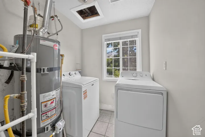 Compact utility area with tiled flooring, a single window, and a ceiling access panel