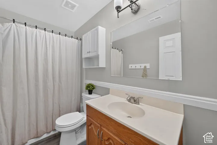 Bathroom featuring wood-finish vanity, integrated sink, and wall-mounted mirror