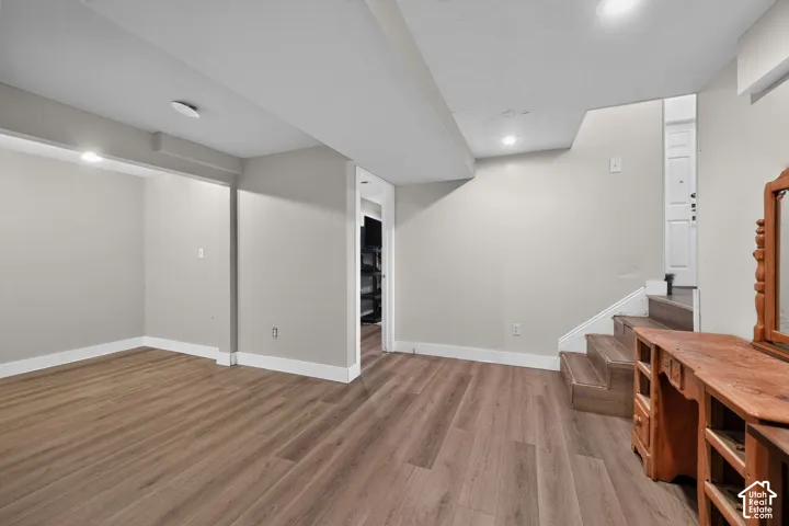 Wood-finish flooring, recessed ceiling lighting, light gray wall paint, and white trim accents