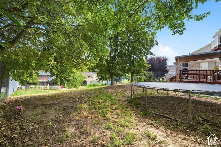 Expansive backyard featuring mature trees, a multi-level deck, and a covered patio area