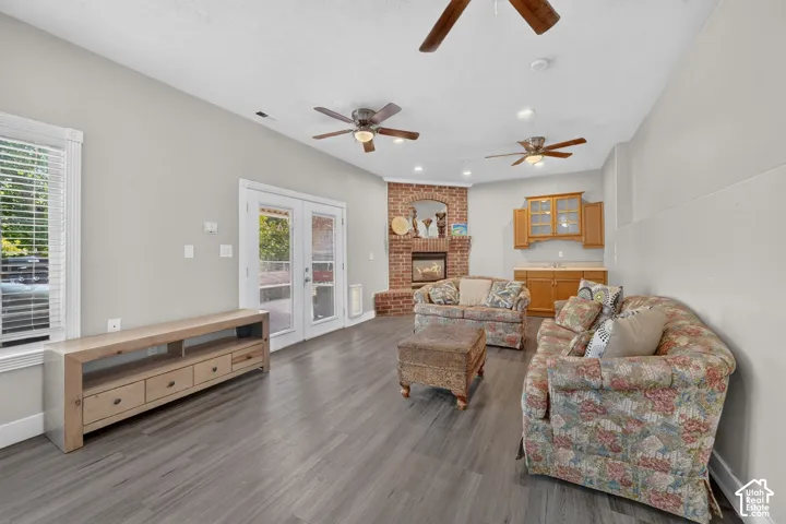 Spacious room featuring wood-finish flooring, a brick fireplace, built-in wet bar with wood cabinetry, and French doors