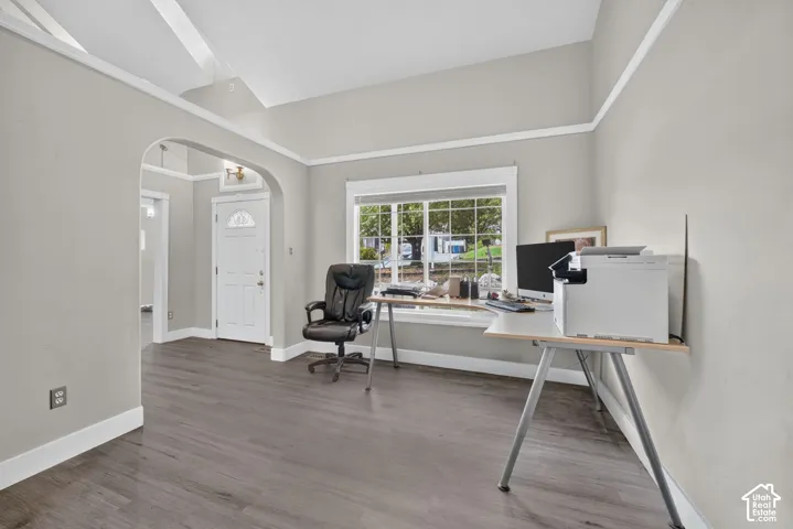 Wood-finish flooring, light gray wall color, white trim, arched doorway, and a white paneled front door