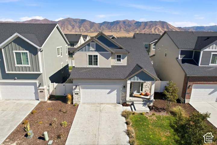 Contemporary exterior featuring mixed siding and stone accents, a covered entry porch, an attached garage, and a concrete driveway