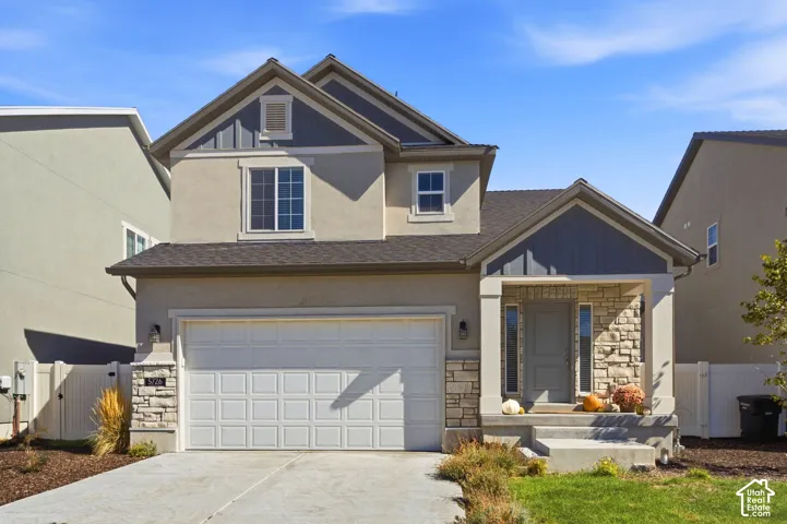 Stucco and stone exterior with an attached garage, covered front porch, and a light gray front door with sidelights