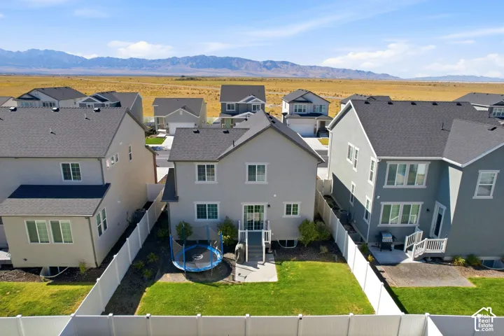 Expansive backyard featuring a manicured lawn, concrete patio, and white vinyl fencing