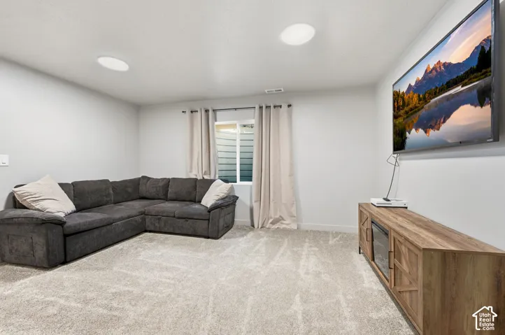 Plush carpeting, recessed ceiling lighting, and a wood-finish media console