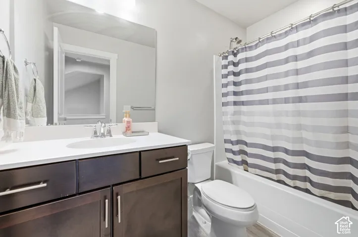 Dark wood-finish vanity with silver-tone hardware, white countertop with integrated sink, chrome-finish faucet, and a large wall-mounted mirror