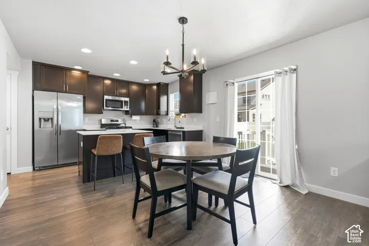Kitchen featuring wood-finish flooring, dark wood cabinetry, white countertops, and stainless steel appliances