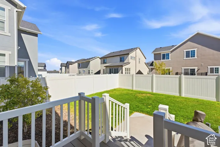 Expansive backyard featuring a manicured lawn, durable white vinyl fencing, and a concrete patio