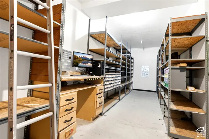 Built-in shelving units, integrated desk with drawers, white walls, and light-toned flooring