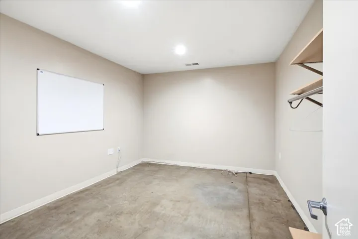 Bare concrete flooring with light-toned walls and built-in shelving