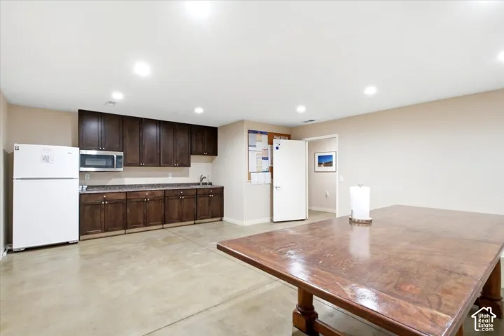 Kitchenette featuring dark wood cabinetry, light-toned countertops, and a stainless steel microwave