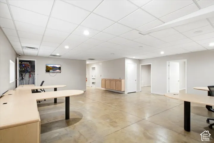 Recessed lighting, drop ceiling, light-colored walls, multiple interior doors, and concrete flooring