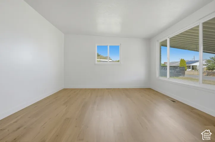 Spacious room with wood-finish flooring, white walls, and large windows