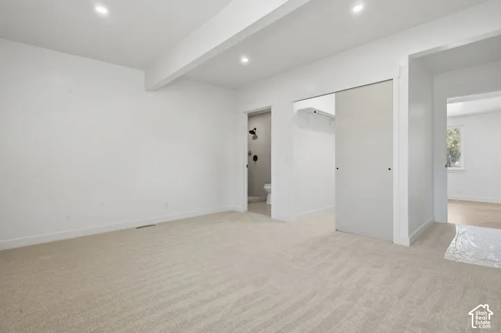 Recessed lighting, light-toned carpeting, white walls, and a sliding closet door