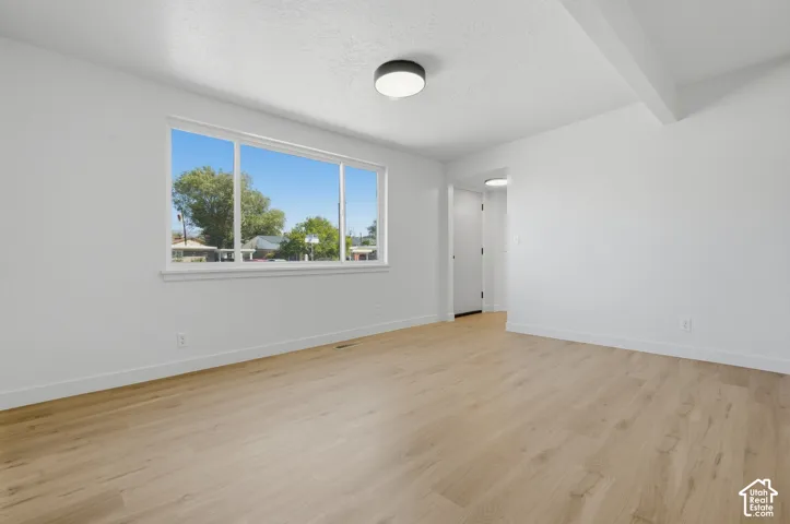 Bright room featuring wood-finish flooring, a large window, a flush-mount ceiling light, and white walls