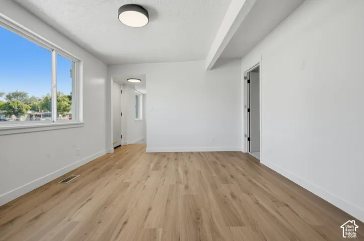 Spacious room featuring wood-finish flooring and white walls
