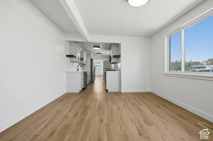 Wood-finish flooring throughout, white walls, and a large window providing ample natural light