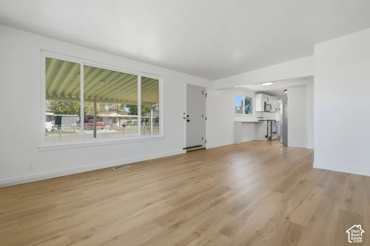Open-concept living area featuring wood-finish flooring, a large picture window, and recessed lighting