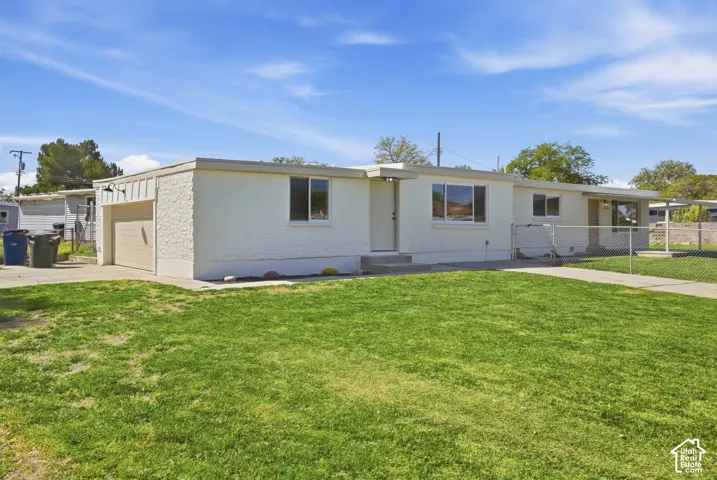 White stucco exterior with an attached garage, covered entryway, and front yard with a concrete pathway
