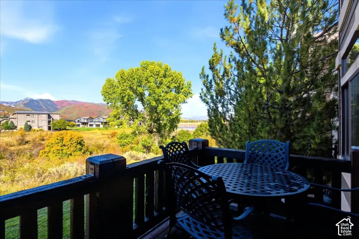 Balcony with dark wood railing overlooking natural terrain with distant mountains
