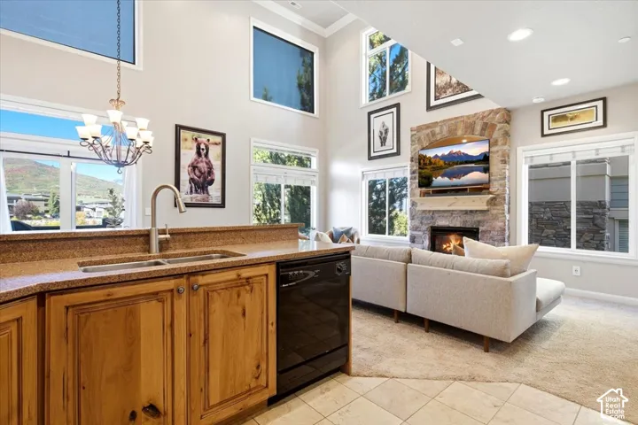 Double-height ceilings, stone-clad fireplace, kitchen island with built-in sink, natural wood cabinetry, and recessed lighting